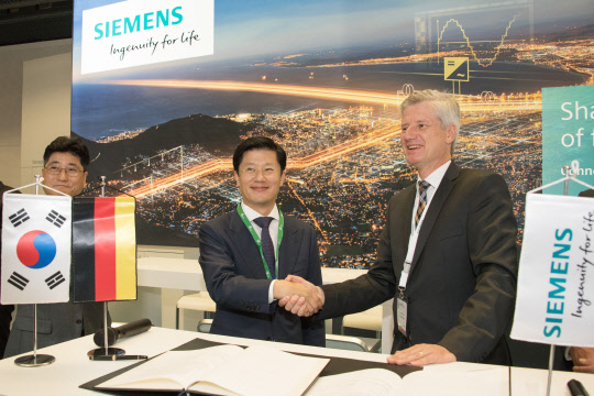 25일(현지시간) 프랑스 파리에서 열린 국제 대전력망 기술협의회(CIGRE)에서 허정석 일진전기 대표(가운데)와 랄프 크리스티안 독일 지멘스 에너지매니지먼트 사업본부 사장이 친환경 가스 절연 개폐장치(GIS) 사업 협력을 위한 양해각서(MOU) 체결식을 한 뒤 악수하고 있다. <일진전기 제공>